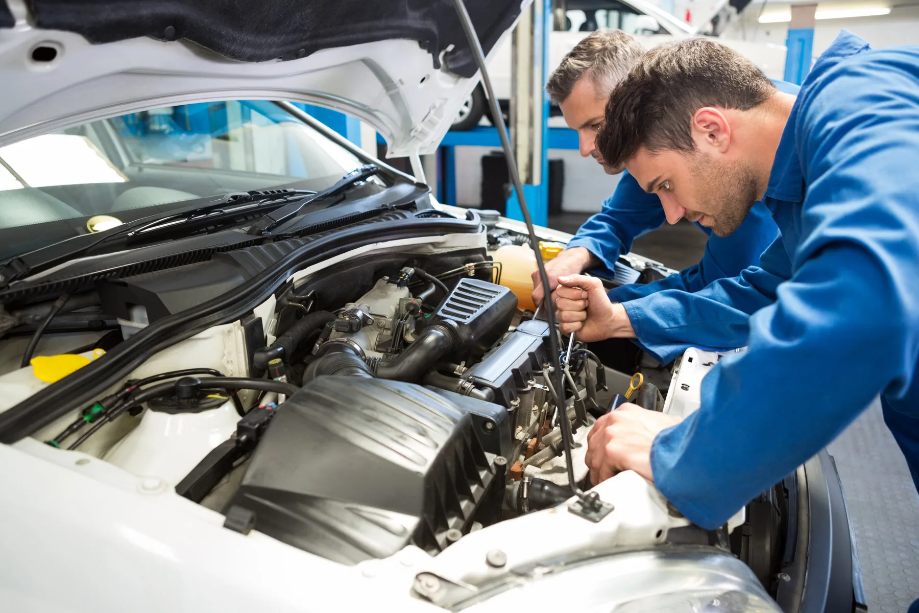 Equipo de mecánicos revisando el motor de un vehículo en un taller automotriz